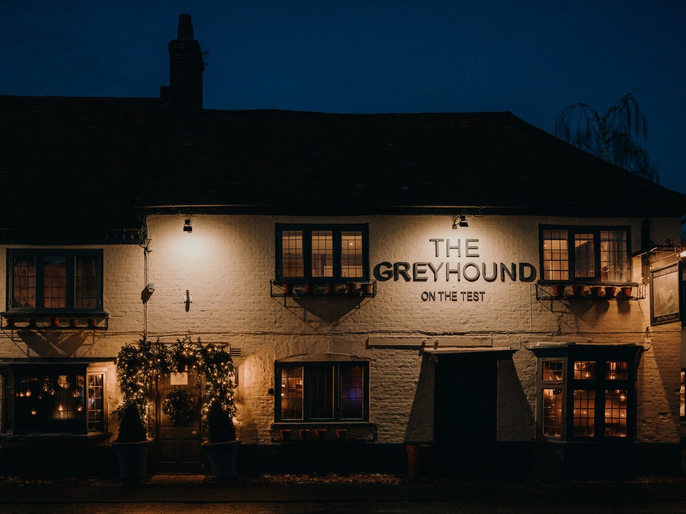 The mustard-coloured exterior of The Greyhound on the Test, a characterful dining pub in Stockbridge