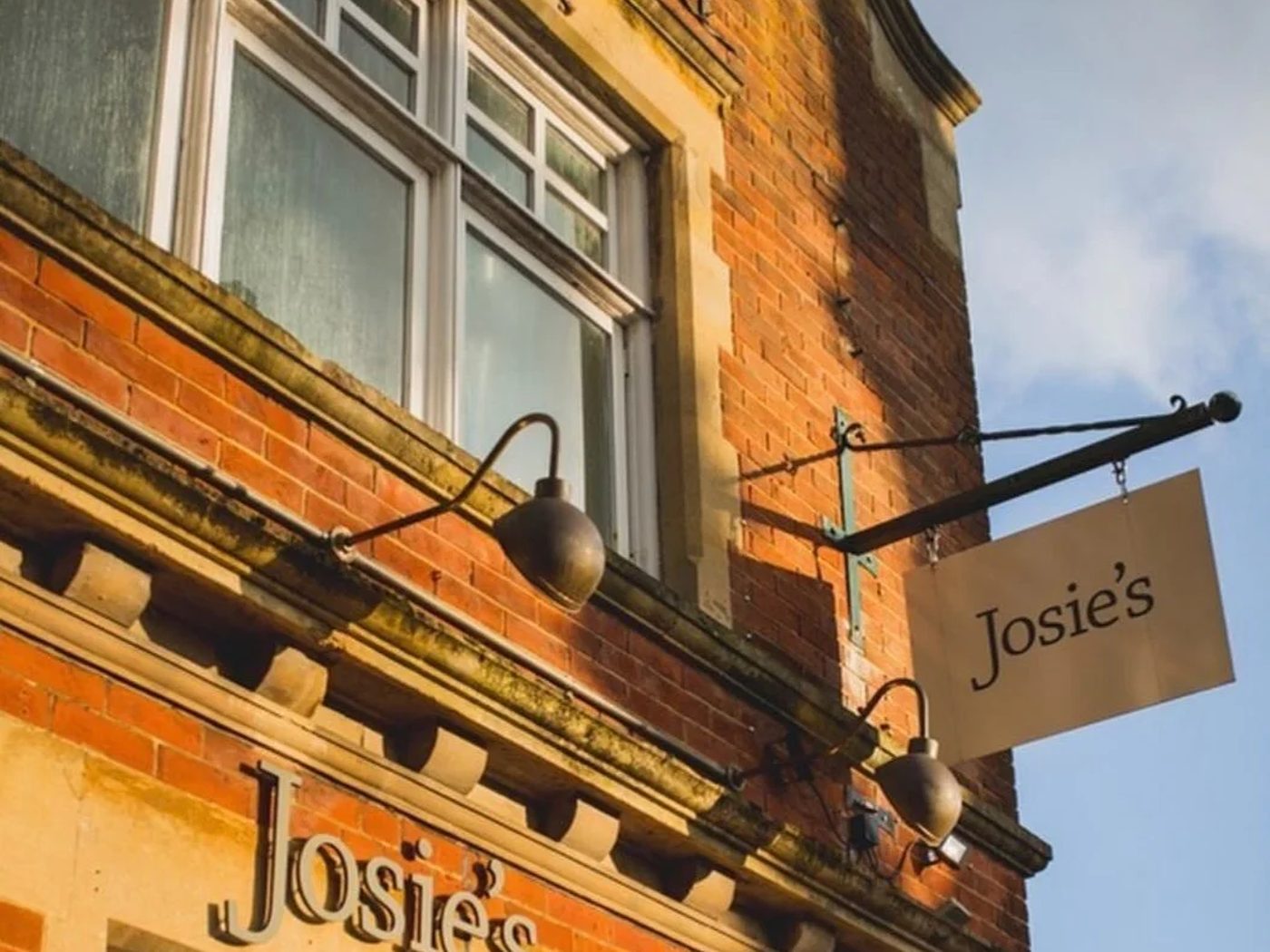 The sunlit brick frontage and hanging sign of a Josie's cafe in Hampshire